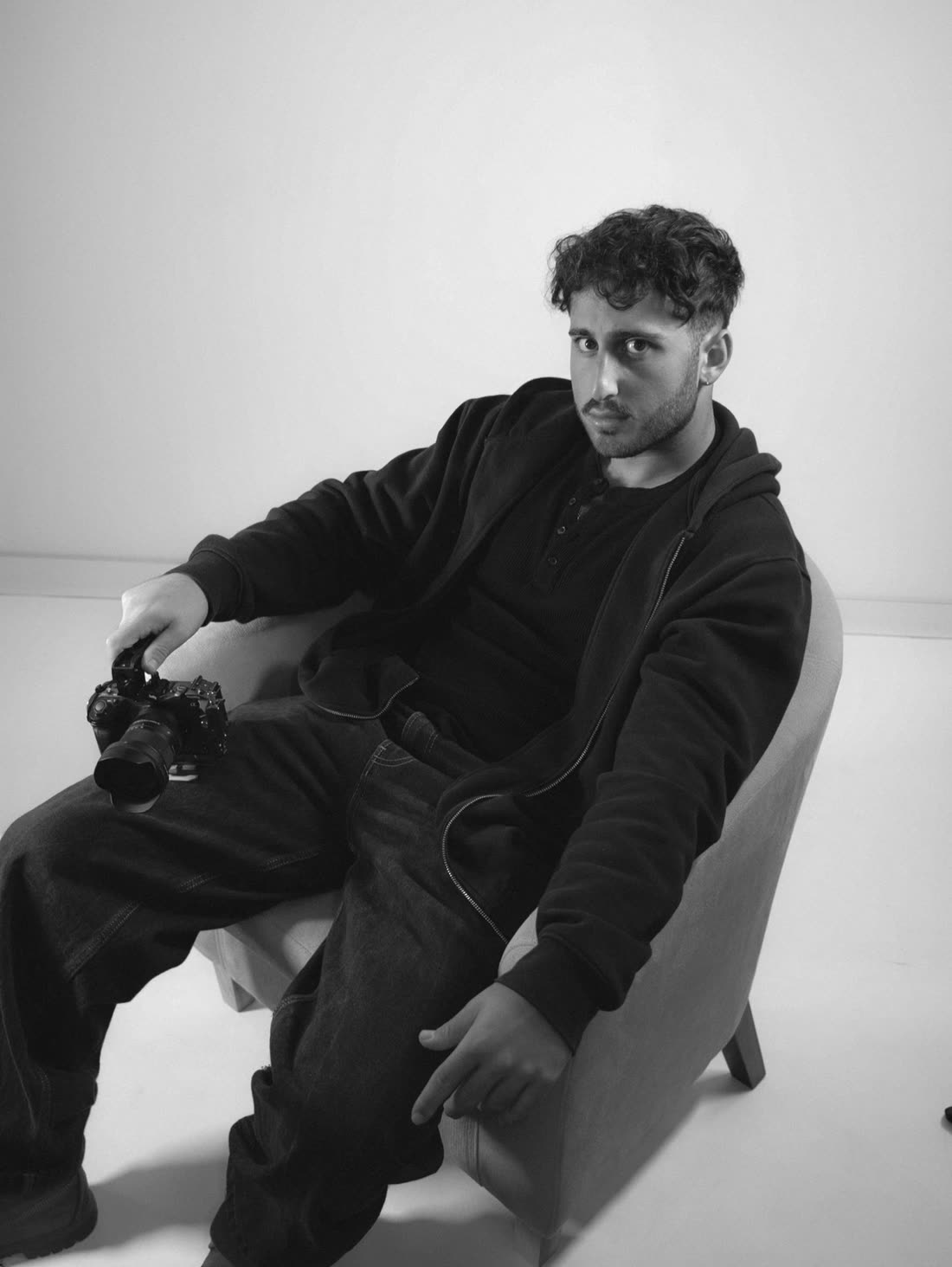Paul-Luke Iliaev seated in an armchair with a camera on his lap